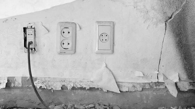 한국의 오래된 건물 내부의 갈라진 벽면과 노출된 전기 콘센트를 담은 흑백 감성 핸드헬드 브이로그 영상
