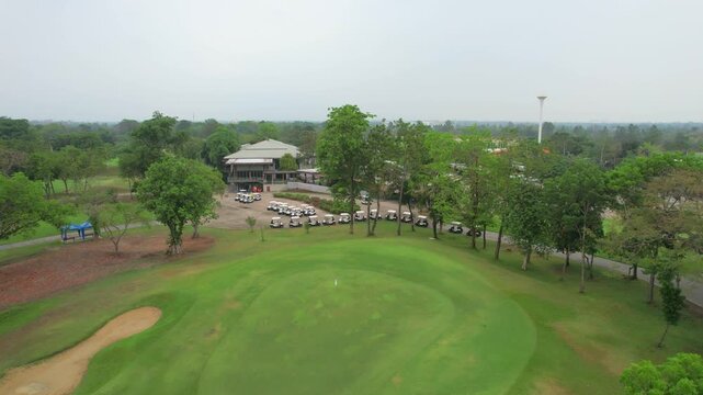 Aerial drone view flying over empty golf course surrounded by lush greenery. 