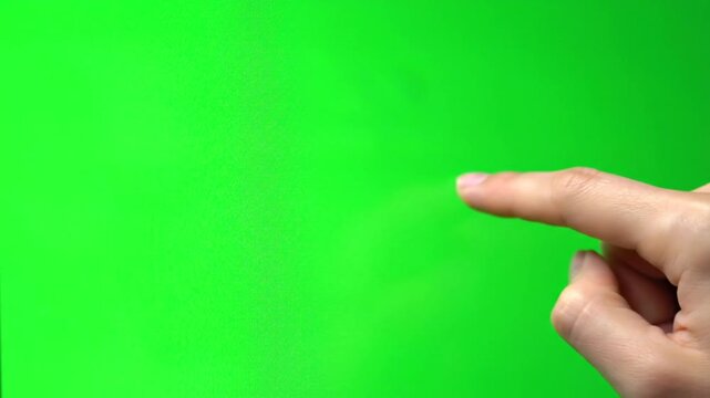 Close-up of a human hand with an index finger pointing on a vibrant green screen background.
