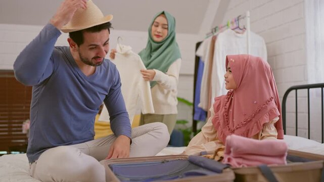 Happy Muslim family preparing clothes and packing suitcase at home. 