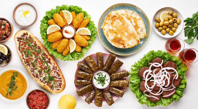 Turkish food flat lay with pide, kofte, lentil soup, mezze, dolma, salads, olives, yogurt dip and flatbread 