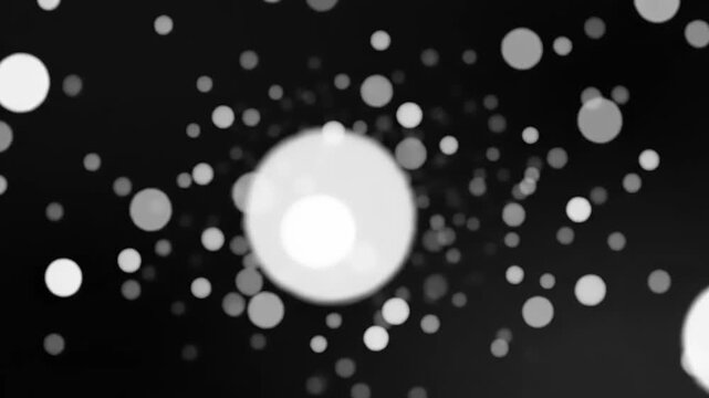 Various white and gray circular objects scattered across a black background creating a dynamic pattern