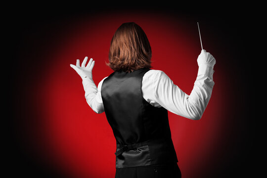 Male conductor on dark red background, back view