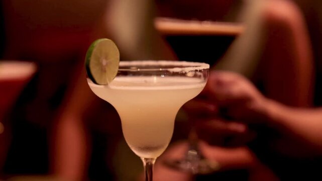 Classic margarita cocktail with lime garnish on salt rimmed glass in dimly lit evening setting.