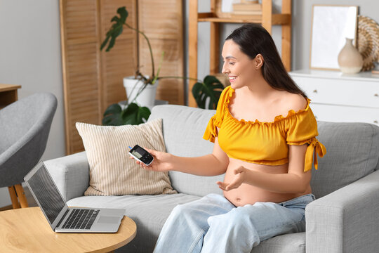 Young pregnant woman with glucometer video chatting at home. Gestational diabetes concept