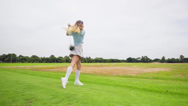 Professional young female golfer swings her club on scenic golf course. 