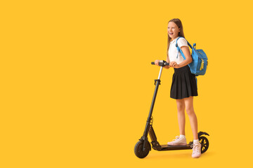 Cute schoolgirl with electric scooter on yellow background © Pixel-Shot