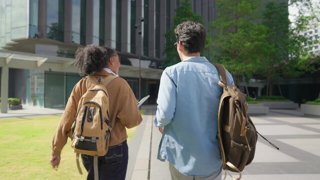 Latino male and African female students walking on campus outdoors. 