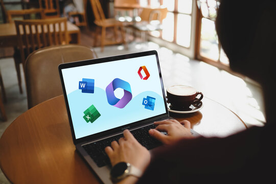 Bangkok, Thailand. April 16, 2026; A person is typing on a laptop displaying Microsoft 365 application icons including Word, Excel, and Outlook on the screen while sitting at a cafe table.