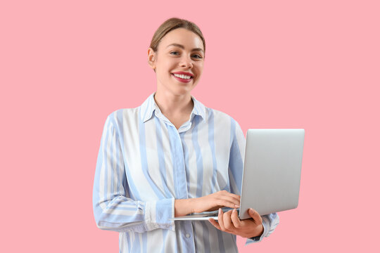 Female programmer working with laptop on pink background
