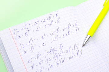 Fototapeta premium Copybook with maths formulas and pen on green background