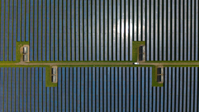 Aerial view of Tutbury solar farm with rows of photovoltaic panels and a white vehicle on a central path Tutbury, England, United Kingdom.