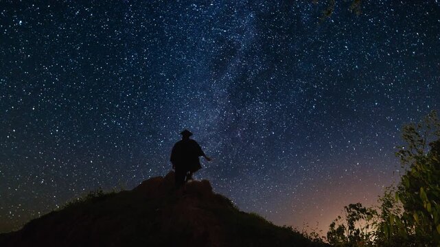 Man climbing a hill to watch the milky way night sky