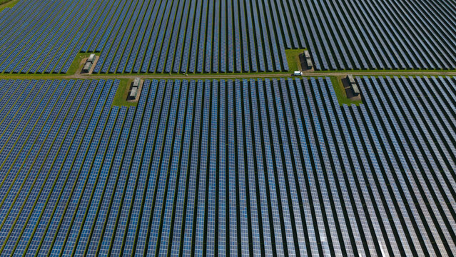 Aerial view of the vast Tutbury solar farm featuring rows of blue photovoltaic panels and a white van on a service road Tutbury, England, United Kingdom.
