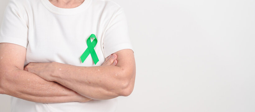 Elderly with Green Ribbon for concept of April Donate Life month, Organ Donation and Transplant Awareness, May Mental Health Awareness month and October Liver cancer. Health and world cancer day