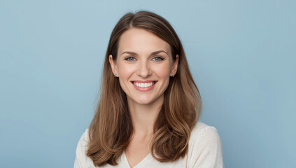 Obraz premium Smiling woman with natural makeup and soft blue background, warm approachable expression