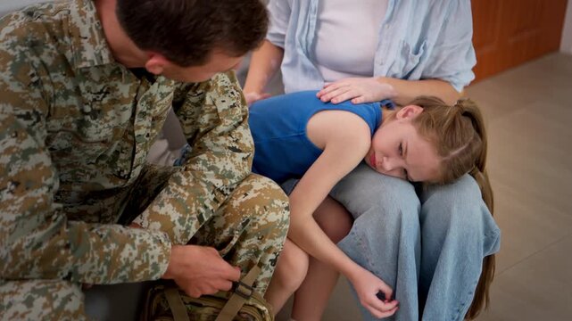 Emotional family moment as soldier comforts his wife and daughter, capturing sadness, love, and the difficulty of saying goodbye