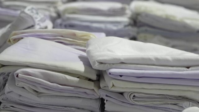Stacks of folded white fabric on a smooth table organized piles clean textile storage preparation material handling.