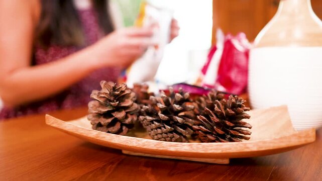 Asian Woman Arranging Pinecones and Essential Oil Diffuser on Wooden Table