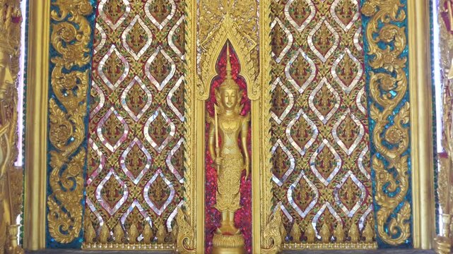 Mythical protector figures across temple wall gilded high relief gold surfaces mirrored details carved borders Thai sacred design reverence grandeur.