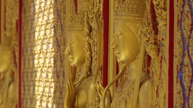 Mythical protector figures across temple wall gilded high relief gold surfaces mirrored details carved borders Thai sacred design reverence grandeur.