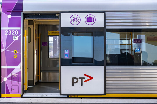 Regional V Line VLocity train carriage with open doors at a platform in Melbourne, featuring bicycle and luggage accessibility icons. Regional public transport infrastructure in Victoria, Australia