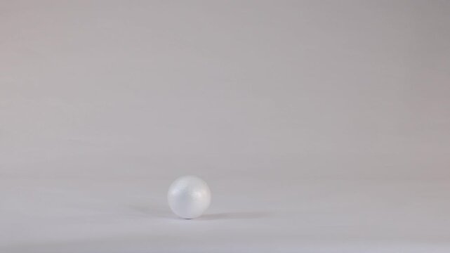 White Styrofoam Ball Bouncing and Rolling on a Plain Studio Background