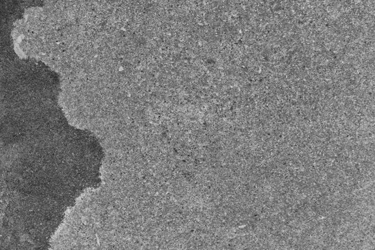 Gray concrete texture background with rough, gritty surface and a dark irregular patch on the side