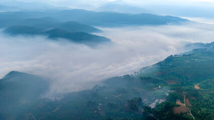 Obraz premium A breathtaking sunrise over layers of misty mountains, where the glowing sun forms a radiant starburst in a golden sky. Soft fog blankets the valleys, creating depth and a dreamy