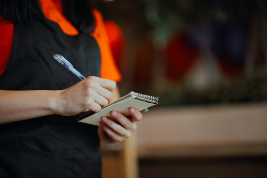 Hands of Waitress Writing Down the Order in a Restaurant. Waitress takes order from customers using pen and paper 

