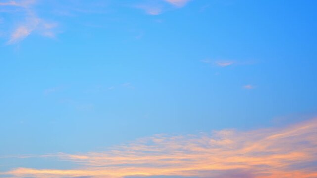A sunset sky timelapse video footage with a wide blue gradient sky and soft orange clouds along the horizon, capturing smooth cloud movement, fading daylight, and a calm, minimalist evening. 4k.
