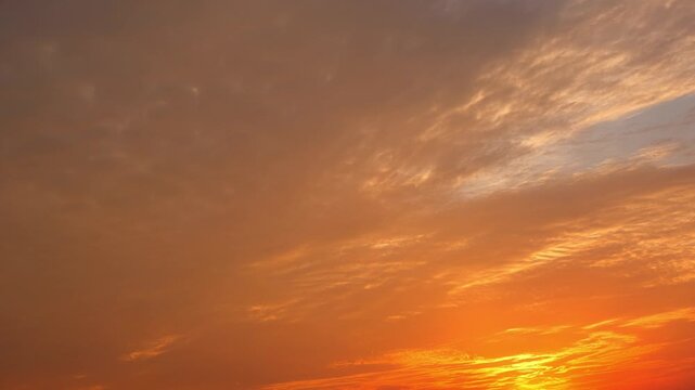 Sunset sky timelapse video footage with glowing orange and golden clouds scattered across a dusky sky, capturing light transitions, textured cloud patterns, and a warm, cinematic evening atmosphere.

