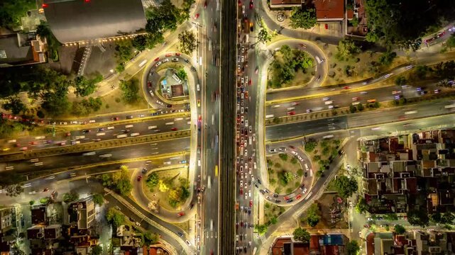 Aerial night hyperlapse of illuminated highway interchange with light trails in Mexico City