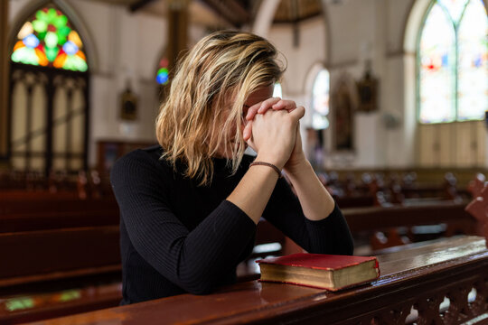 Woman praying inside church pew.