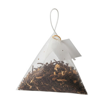 A pyramid shaped tea bag filled with black tea leaves isolated on transparent background