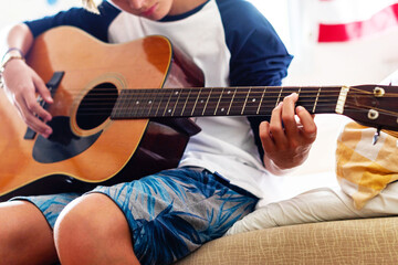Fototapeta premium Teen playing acoustic guitar indoors