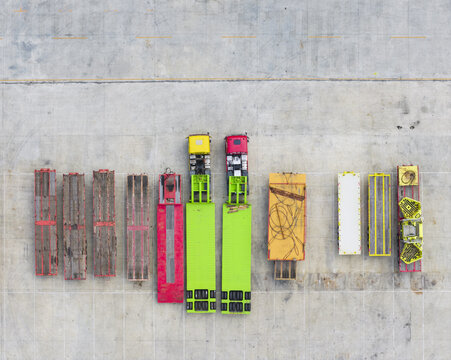 Aerial view of colorful trucks and trailers parked in a row on a concrete industrial lot Taiwan.