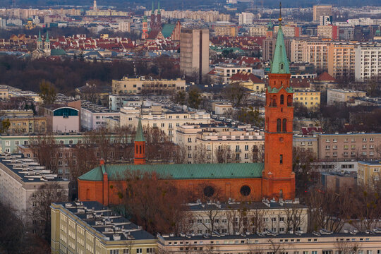 Aerial view of the historic St. Augustine's Church with its tall green spire and red brick facade surrounded by urban residential buildings in Warsaw, Masovian Voivodeship, Poland.