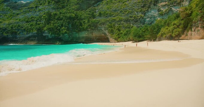 Tourists relaxing on tropical pristine sandy beach Kelingking Bali Nusa Penida