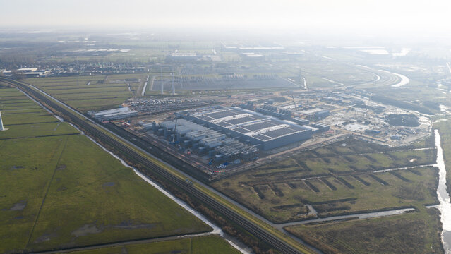 Aerial view of the Datacenter Westpoort industrial complex surrounded by green fields and drainage canals under a hazy sky in Groningen, Groningen, Netherlands.