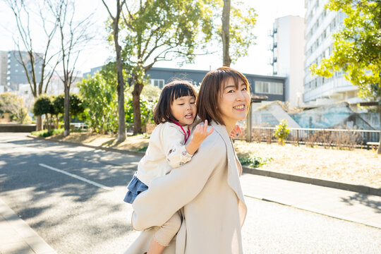 Smiling Japanese Mother and Toddler Daughter Looking Up at the Trees in a Sunny Park
