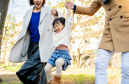 Joyful Japanese parents lifting their little daughter high towards the sunlight in a bright winter park, family happiness
Keywords:
