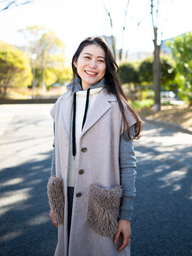 Portrait of a Smiling Mature Japanese Woman Wearing Trendy Layered Outfit in a Park