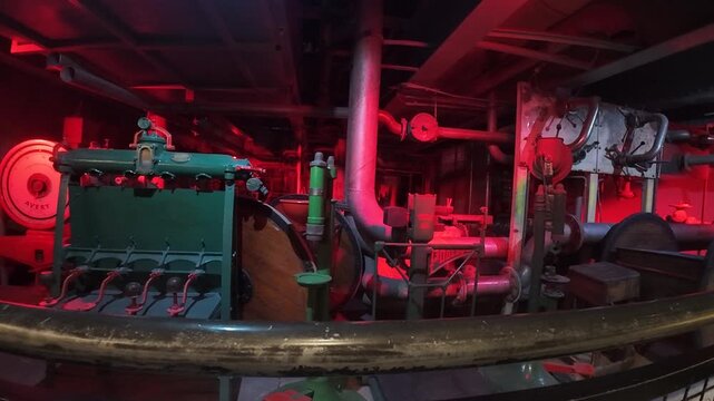 Industrial equipment, metal pipes, valves and tanks inside Guinness Storehouse Dublin Ireland, illuminated with red light showing brewery process environment and engineering details
