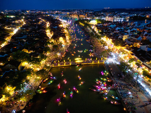 Aerial view of Hoi An ancient town at night with colorful lantern boats on the Thu Bon River and illuminated historic buildings Hoi An, An Giang, Vietnam.