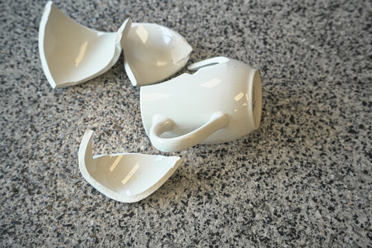 Smashed broken chinaware teacup pieces on floor