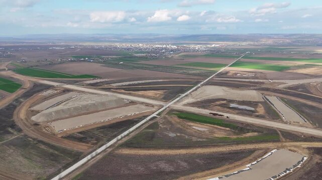Drone pullback shot revealing a large highway interchange under construction near Pașcani, Romania, part of the A7 and A8 motorway network