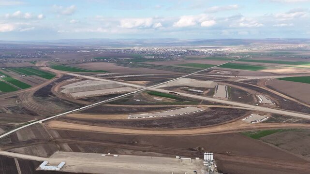 Wide drone shot of a major highway interchange under construction near Pașcani, Romania, part of the A7 and A8 motorway network