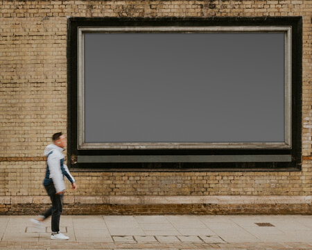 Urban billboard with walking pedestrian, suitable as mockup