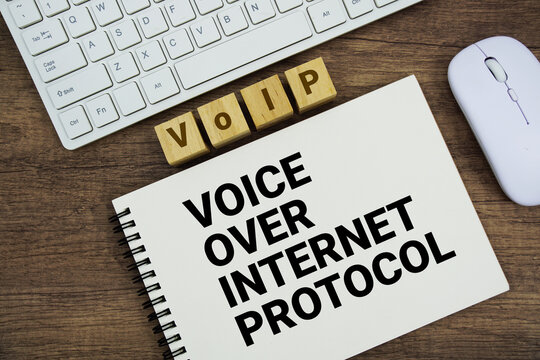 VoIP Voice over Internet Protocol message with keyboard and optical mouse on wooden background